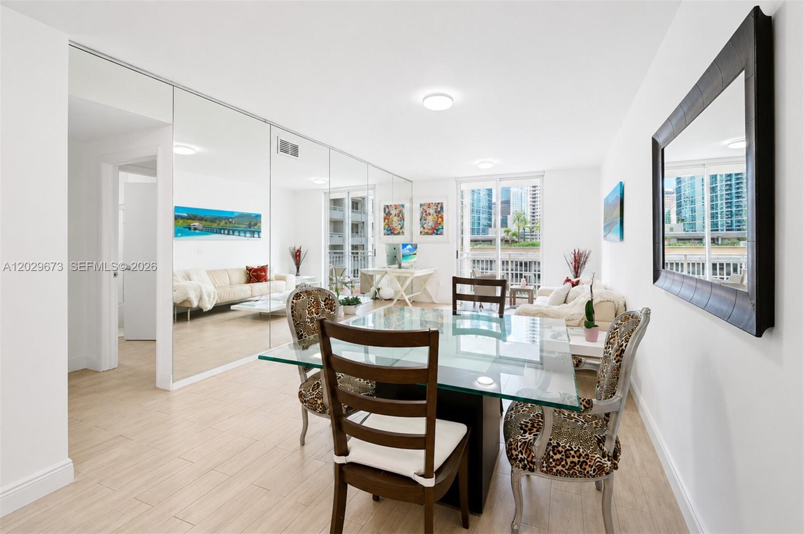 A dining area with a glass table, leopard-print chairs, and a large mirrored wall — 185 SE 14th Ter # 1410, Miami FL 33131, MIAMI, FL