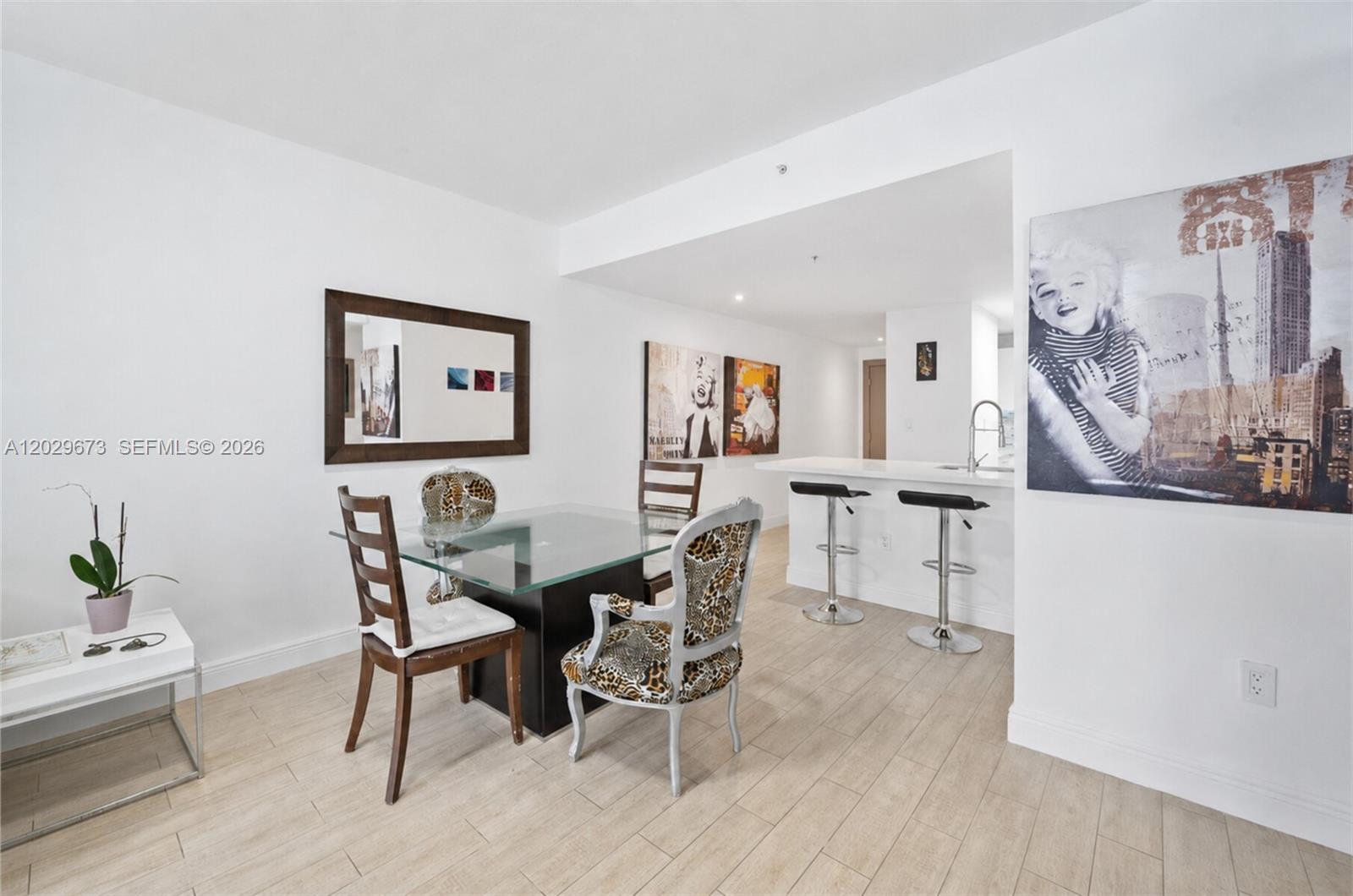 A dining area with a glass table, mixed chairs, and a breakfast bar with stools — 185 SE 14th Ter # 1410, Miami FL 33131, MIAMI, FL