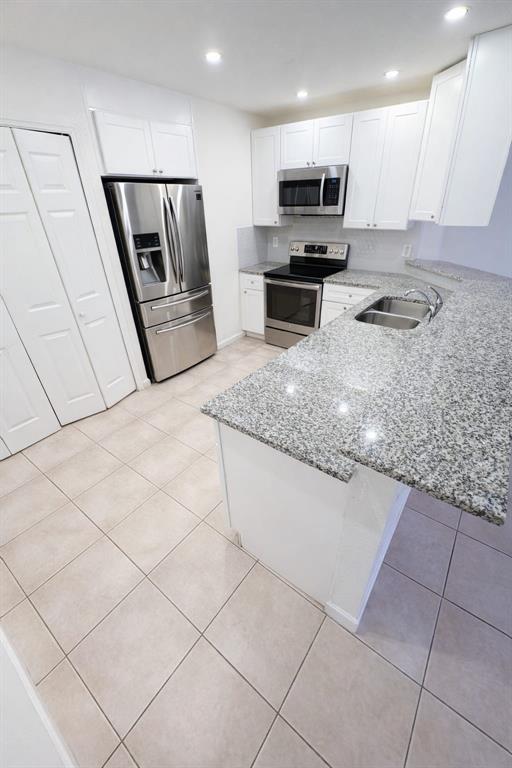 A kitchen features white cabinets, stainless steel appliances, granite countertops, and light-colored tile flooring — 627 BLUEBILL COURT, KISSIMMEE, FL