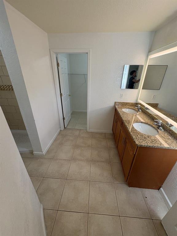 A bathroom features a double vanity with granite countertops, tiled floors, and an adjacent closet — 627 BLUEBILL COURT, KISSIMMEE, FL