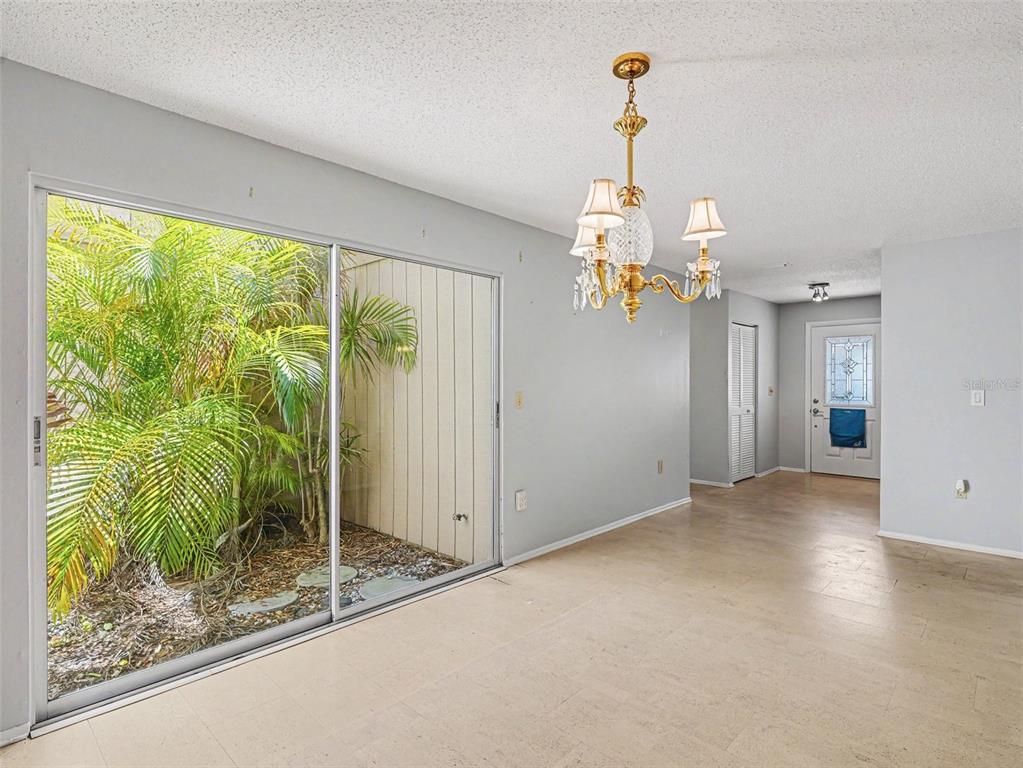 A dining room with tile floors, a crystal chandelier, and sliding glass doors to a patio — 3506 AUBURN COURT UNIT 230, SARASOTA, FL