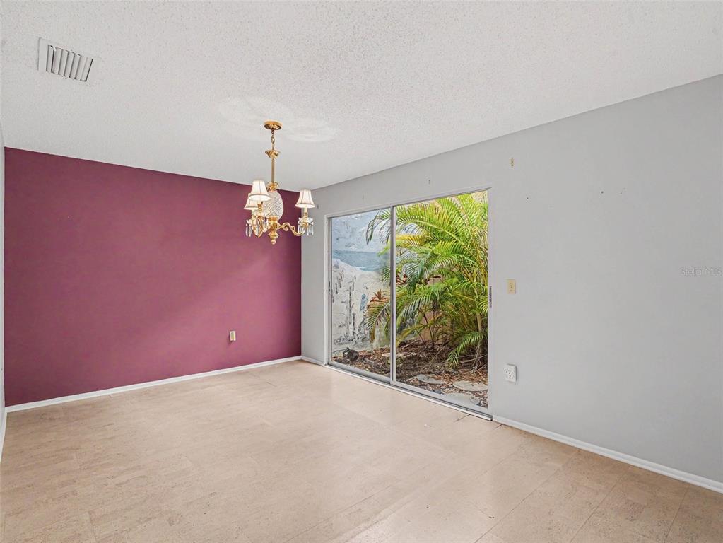A dining room features a purple accent wall, a chandelier, and sliding glass patio doors — 3506 AUBURN COURT UNIT 230, SARASOTA, FL
