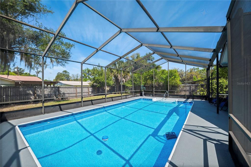 A rectangular swimming pool is enclosed by a screened-in lanai with a concrete deck — 1516 PROSPECT STREET, PALATKA, FL