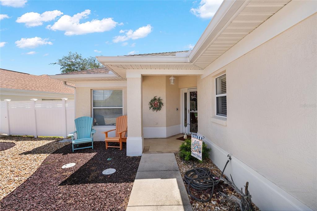 A beige house exterior features a front porch with two Adirondack chairs and a walkway — 17239 SE 84TH KNIGHT AVENUE, THE VILLAGES, FL