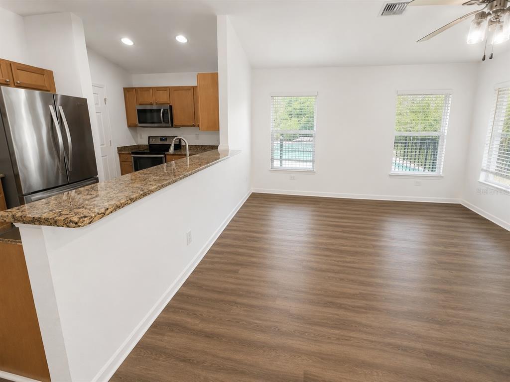 An open-concept kitchen with wood cabinets and granite counters overlooks a spacious living area — 27349 ALOHA DRIVE, PUNTA GORDA, FL