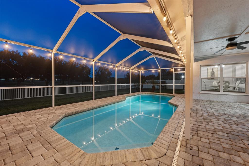 A screened-in swimming pool with paver decking at dusk — 2410 ARBORWOOD DRIVE, VALRICO, FL