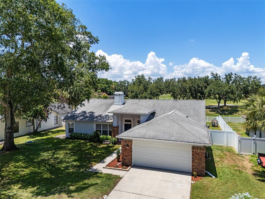 An aerial view shows a single-story house with a brick-accented garage and a large lawn — 2410 ARBORWOOD DRIVE, VALRICO, FL