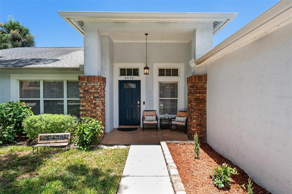 The exterior of a house features a blue front door, brick columns, and a walkway — 2410 ARBORWOOD DRIVE, VALRICO, FL