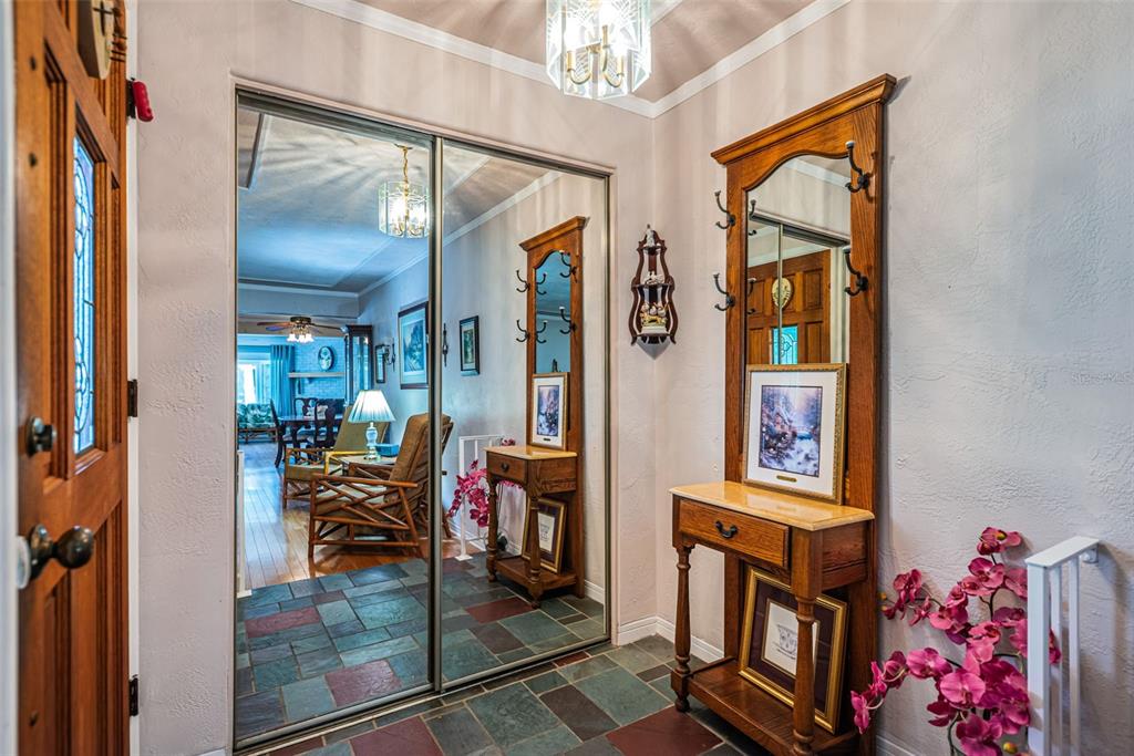 An entryway features a slate tile floor, a mirrored closet, and a wooden hall tree — 13940 87TH AVENUE, SEMINOLE, FL