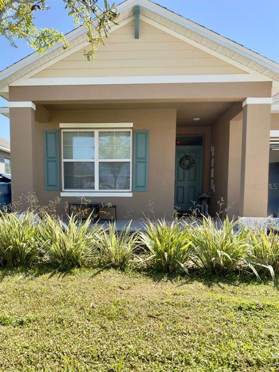 A single-story house exterior features a tan stucco facade, blue shutters, and a front porch — 295 TAYLOR GROVES STREET, LAKE WALES, FL