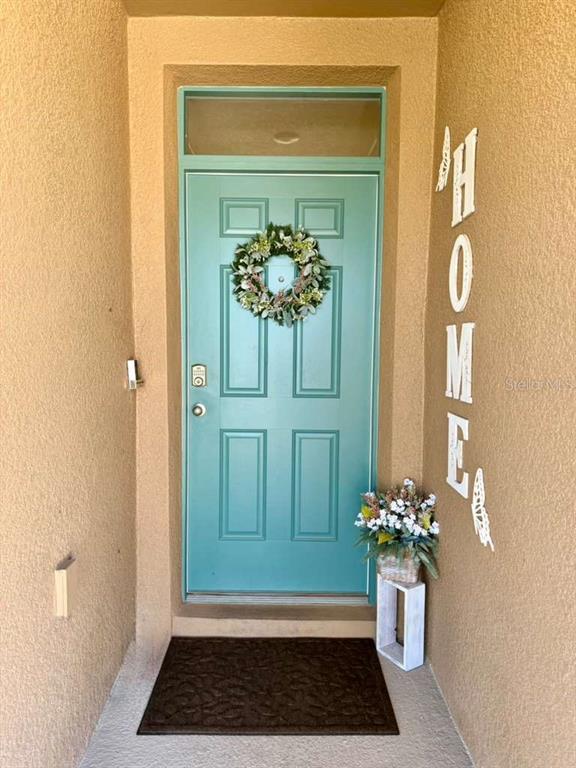 A teal front door with a wreath and a vertical "HOME" sign on the wall — 295 TAYLOR GROVES STREET, LAKE WALES, FL