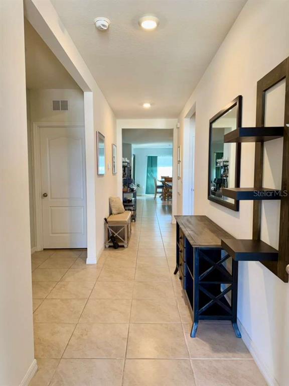 A hallway with tile flooring leads to an open living area with a console table — 295 TAYLOR GROVES STREET, LAKE WALES, FL