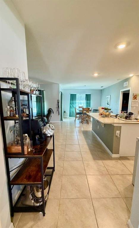 A kitchen with a breakfast bar, tile flooring, and a metal shelving unit in the foreground — 295 TAYLOR GROVES STREET, LAKE WALES, FL