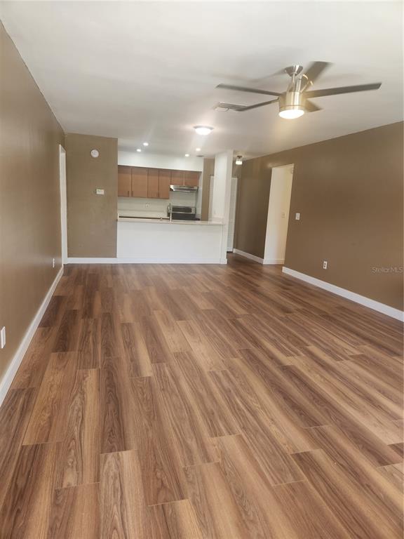 A living area with wood-look flooring leads to an open kitchen with a breakfast bar — 13608 S VILLAGE DRIVE UNIT 6204, TAMPA, FL