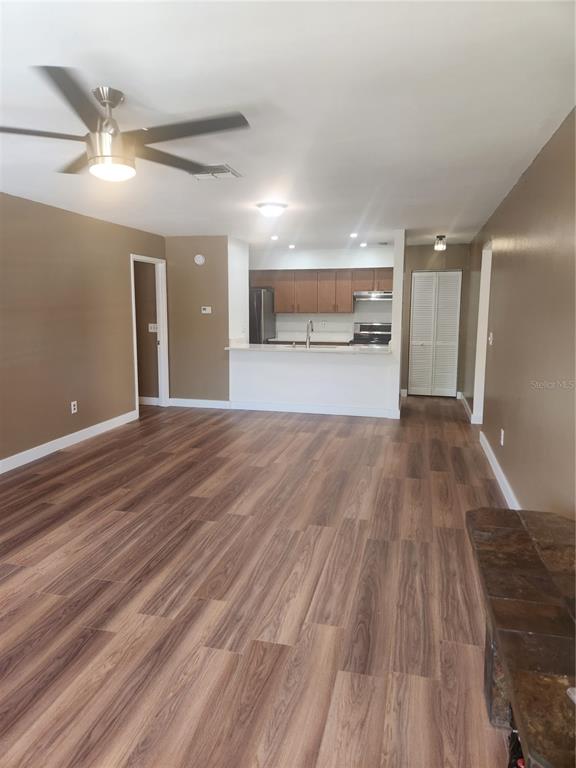 An open-concept living area features wood-look flooring, a ceiling fan, and a kitchen with cabinets — 13608 S VILLAGE DRIVE UNIT 6204, TAMPA, FL
