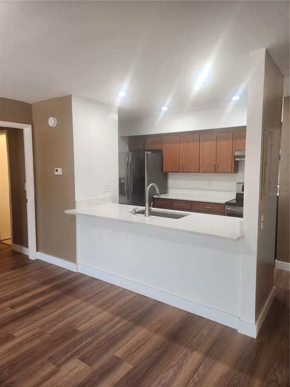 A kitchen with wood cabinets, stainless steel appliances, and a white breakfast bar countertop — 13608 S VILLAGE DRIVE UNIT 6204, TAMPA, FL