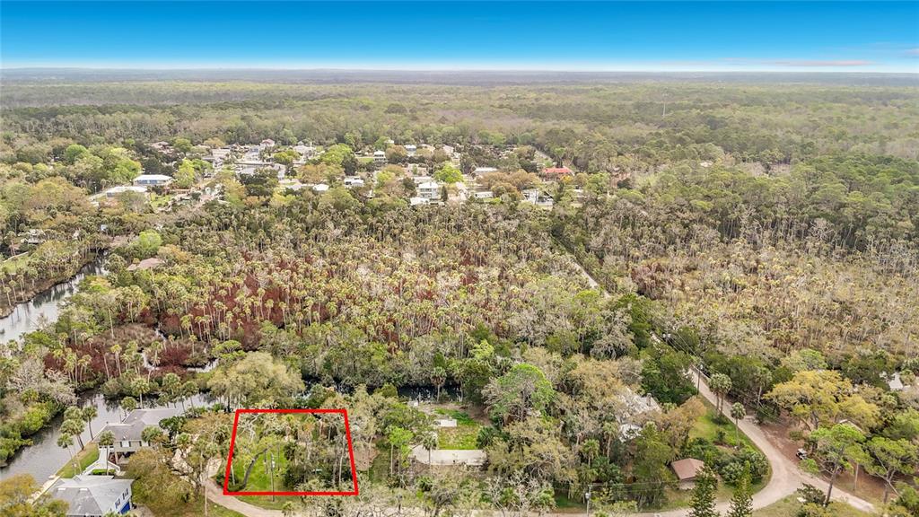 An aerial view shows a wooded residential area with a red-outlined vacant lot — 5360 FELKER DRIVE, WEEKI WACHEE, FL