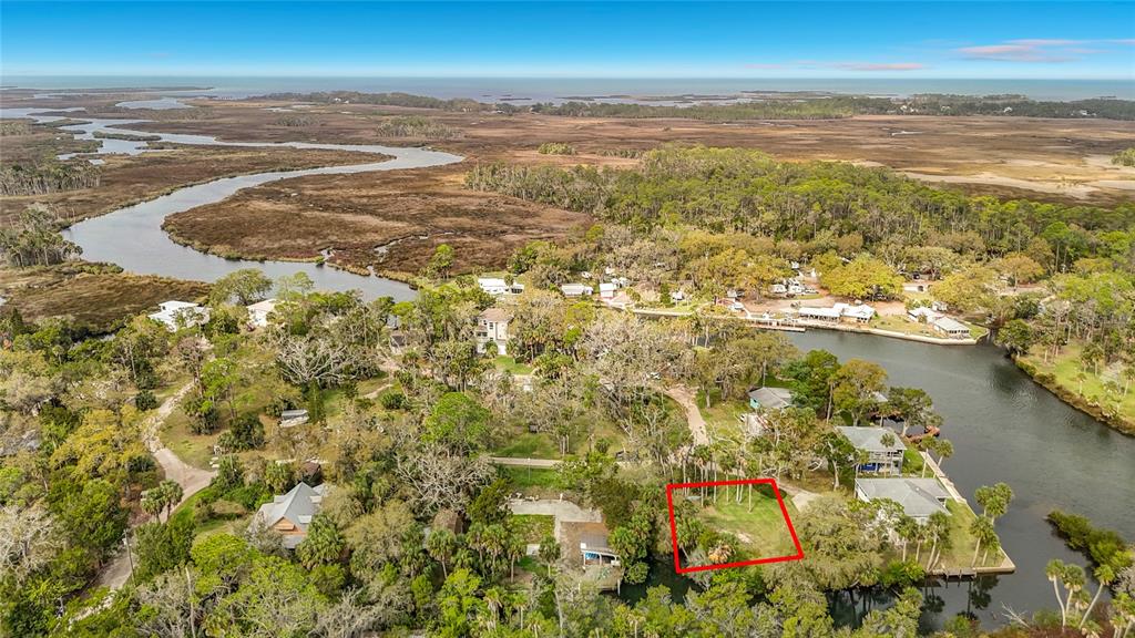 An aerial view shows a vacant waterfront lot outlined in red within a wooded area — 5360 FELKER DRIVE, WEEKI WACHEE, FL