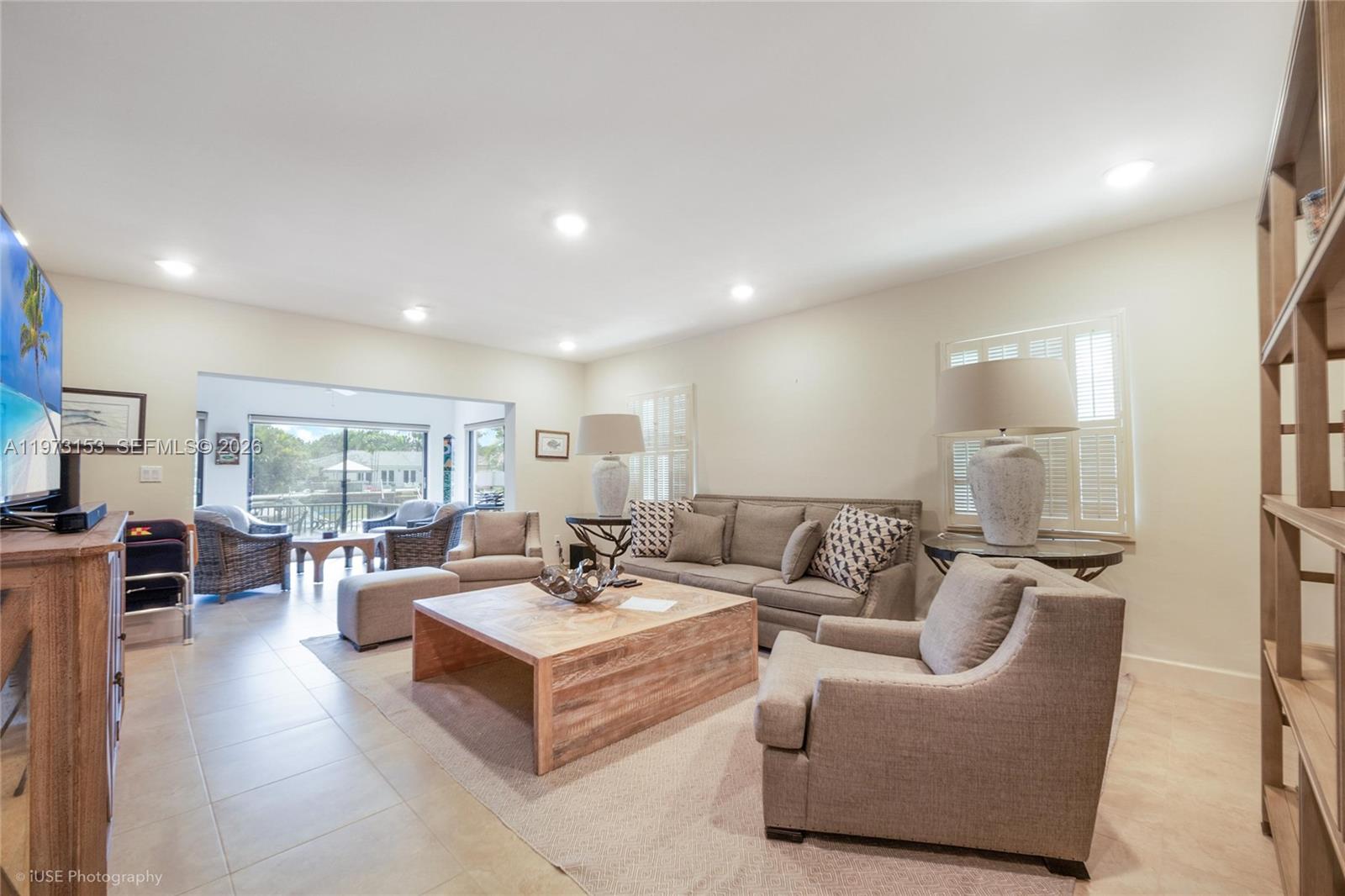 A living room features a large wooden coffee table, grey sofa, and an adjacent patio — 1265 S Alhambra Cir # A, Coral Gables FL 33146, CORAL GABLES, FL