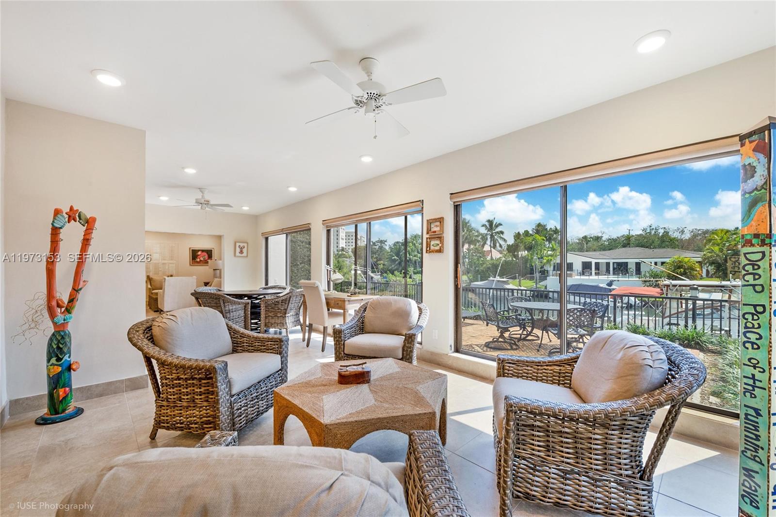 A sunlit living room features wicker furniture, a hexagonal coffee table, and large sliding glass doors — 1265 S Alhambra Cir # A, Coral Gables FL 33146, CORAL GABLES, FL
