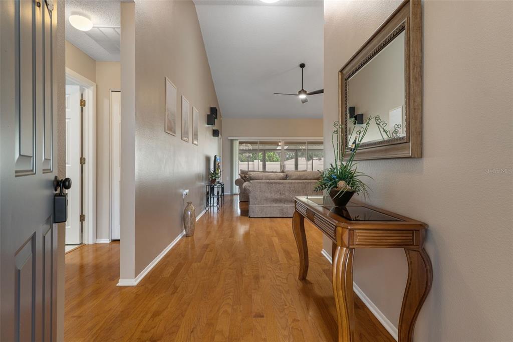 A view from an entryway looking into a living room with hardwood floors and vaulted ceilings — 1424 PINEWOOD HILLS COURT, SPRING HILL, FL