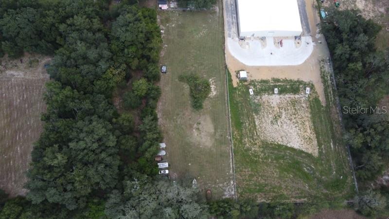 An aerial view shows a rectangular vacant lot situated between a wooded area and a building — 35433 MICRO RACETRACK ROAD, FRUITLAND PARK, FL