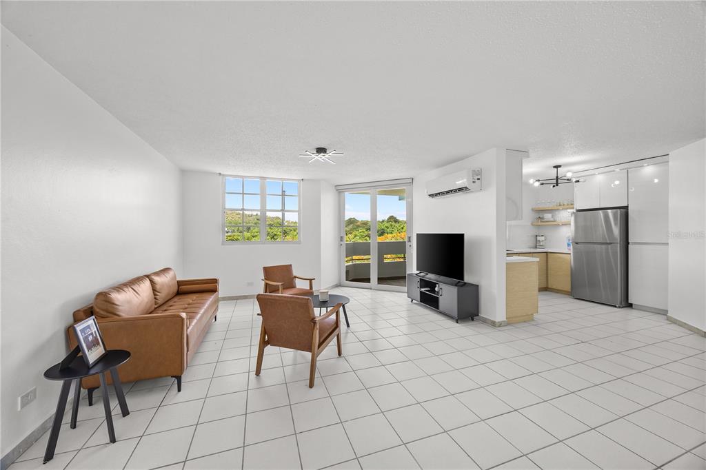 A bright living room with white tile floors, a leather sofa, and an open kitchen — VIA PEDREGAL COND MONTECILLO COURT VIA PEDREGAL APT #4808 UNIT 48, TRUJILLO ALTO, PR