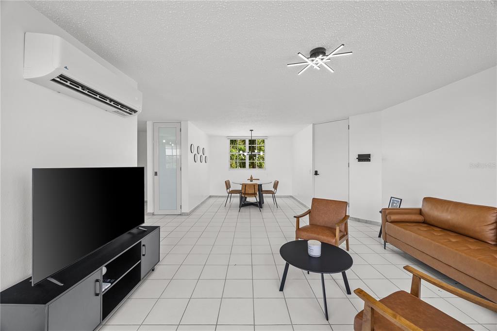 A living and dining area with white tile floors, a leather sofa, and an air conditioner — VIA PEDREGAL COND MONTECILLO COURT VIA PEDREGAL APT #4808 UNIT 48, TRUJILLO ALTO, PR