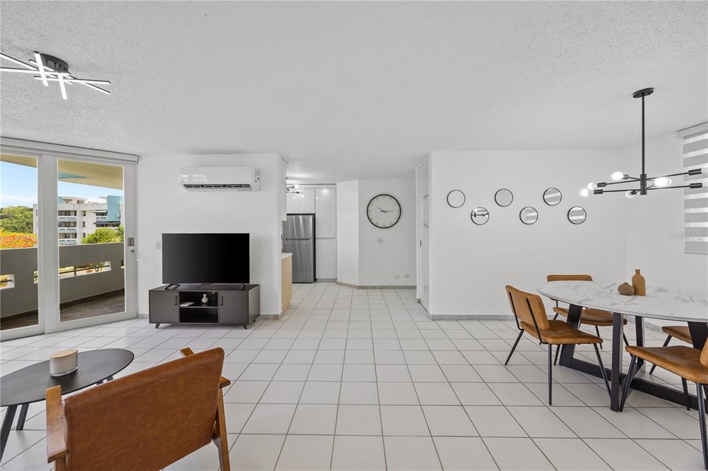 An open-concept living and dining area features white tile floors, a balcony, and modern furniture — VIA PEDREGAL COND MONTECILLO COURT VIA PEDREGAL APT #4808 UNIT 48, TRUJILLO ALTO, PR