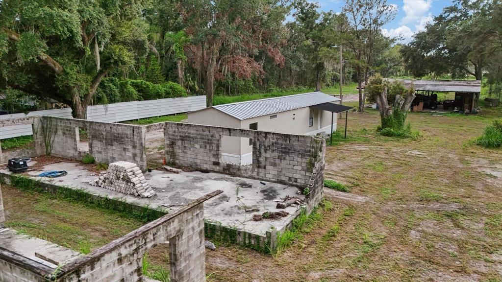An aerial view shows a concrete block structure shell and a nearby mobile home — 2102 SYDNEY DOVER ROAD, DOVER, FL