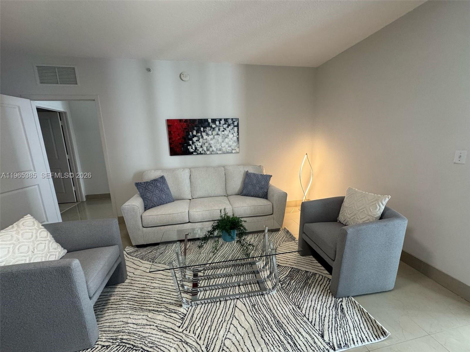 A living room features a light-colored sofa, two gray armchairs, and a glass coffee table — 170 SE 14th St # 1108, Miami FL 33131, MIAMI, FL