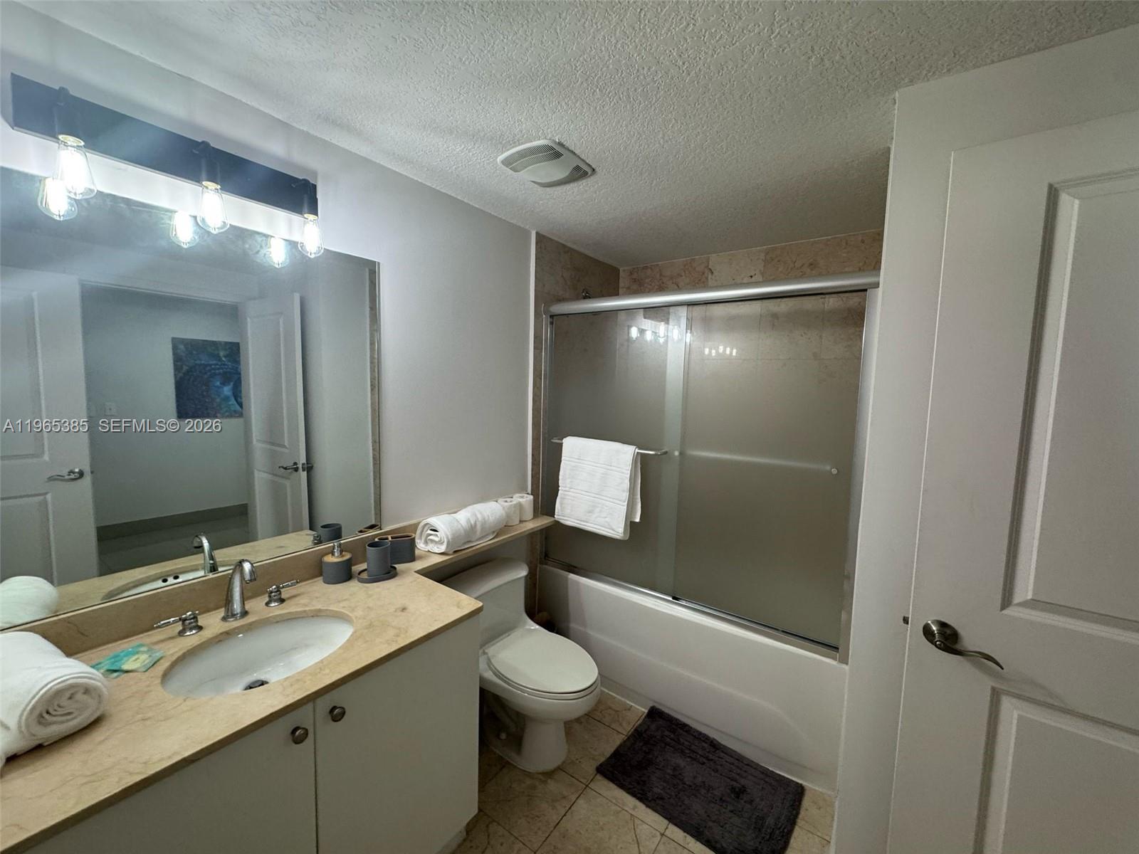 A bathroom features a vanity with a beige countertop, a toilet, and a shower-tub combo — 170 SE 14th St # 1108, Miami FL 33131, MIAMI, FL