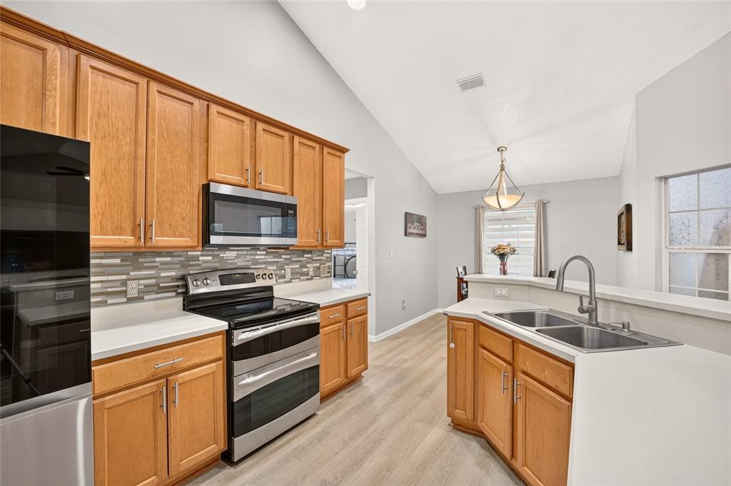 A kitchen with wood cabinets, stainless steel appliances, a tile backsplash, and light-colored flooring — 11213 NW 34TH AVENUE, GAINESVILLE, FL