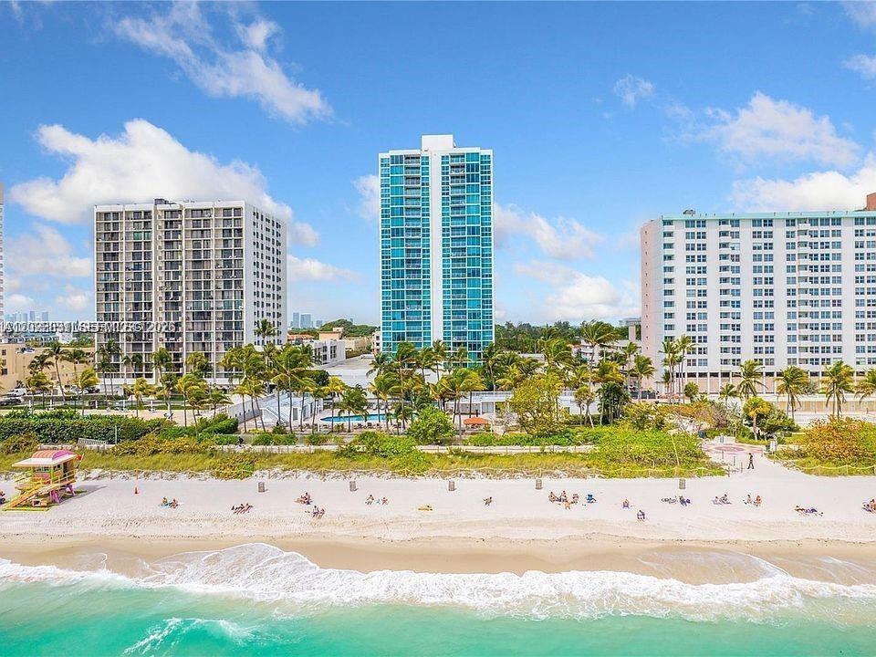 An aerial view of a sandy beach with three high-rise buildings and a lifeguard tower — 2655 Collins Ave # 2302, Miami Beach FL 33140, MIAMI BEACH, FL