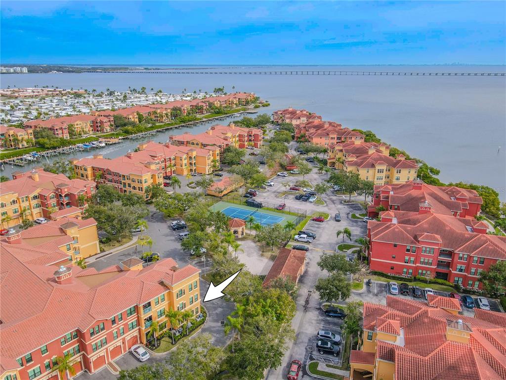 An aerial view shows a multi-story apartment complex with red roofs and a tennis court — 2722 VIA TIVOLI UNIT 410A, CLEARWATER, FL