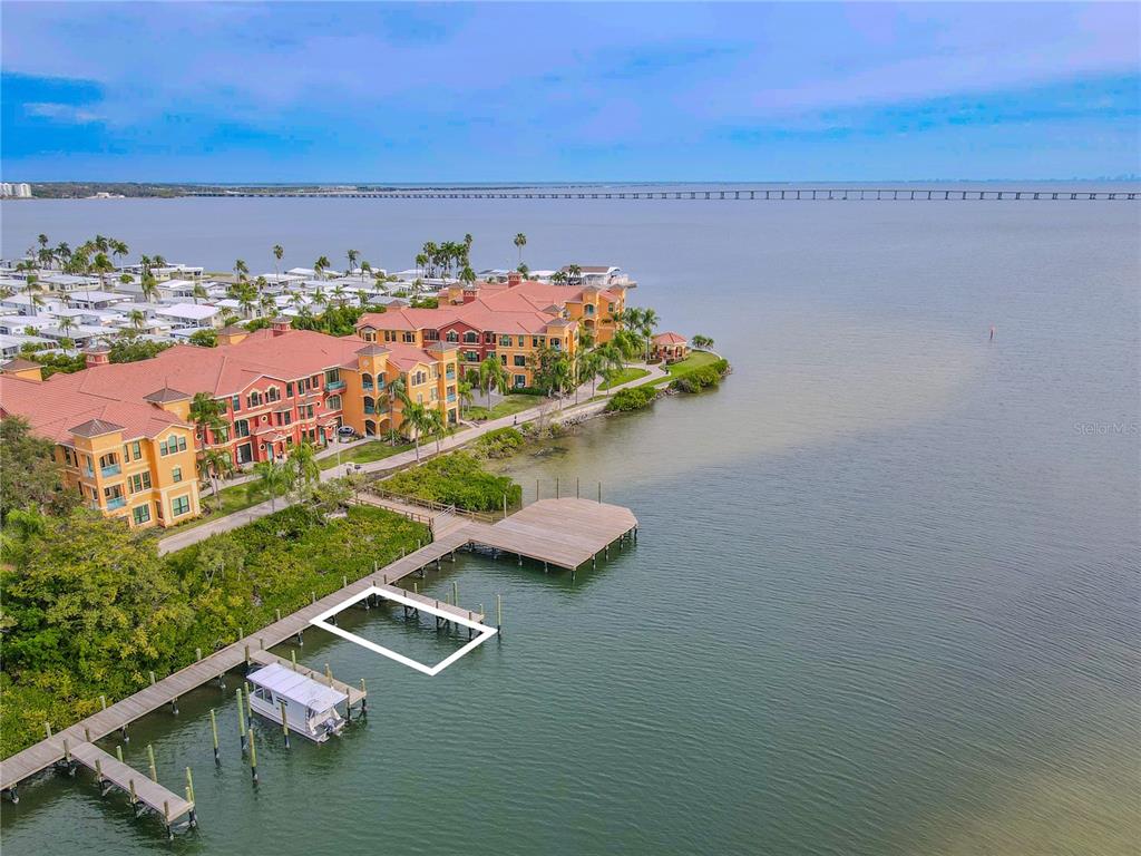 An aerial view shows a waterfront apartment complex with a wooden dock and boat slip — 2722 VIA TIVOLI UNIT 410A, CLEARWATER, FL