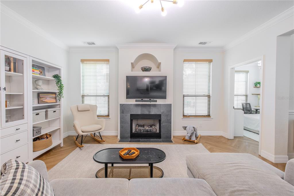 A living room features a fireplace with a mounted television, a rocking chair, and shelving — 2722 VIA TIVOLI UNIT 410A, CLEARWATER, FL