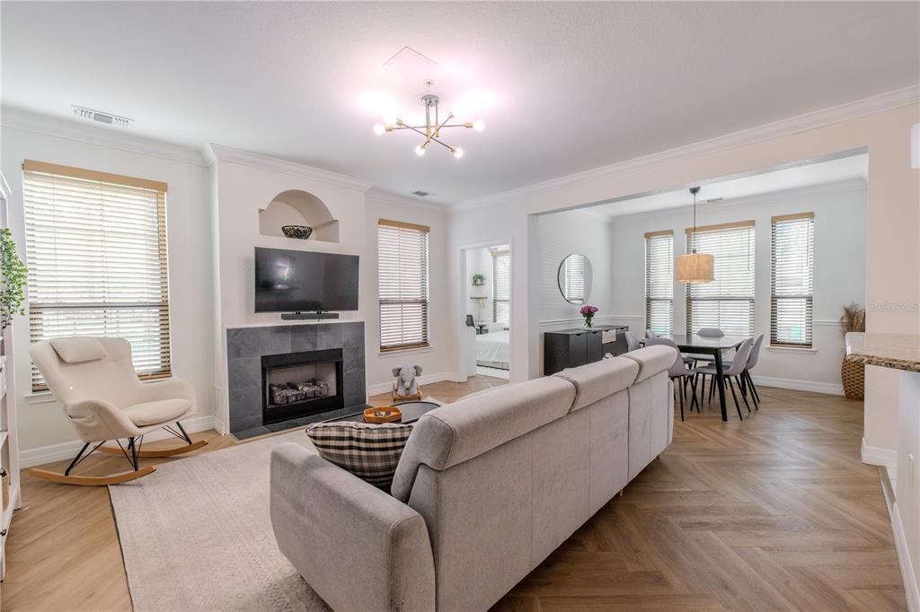 A living room with a fireplace, sofa, rocking chair, and an adjacent dining area — 2722 VIA TIVOLI UNIT 410A, CLEARWATER, FL