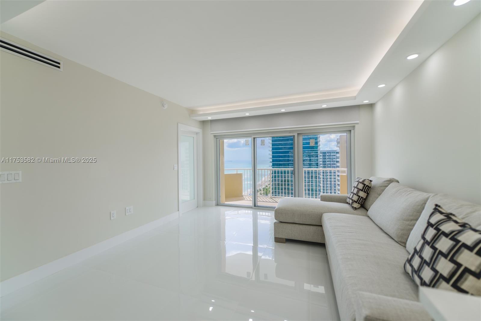 A bright living room features white tile floors, a sectional sofa, and a balcony view — 1950 S Ocean Dr # 20L, Hallandale Beach FL 33009, HALLANDALE BEACH, FL