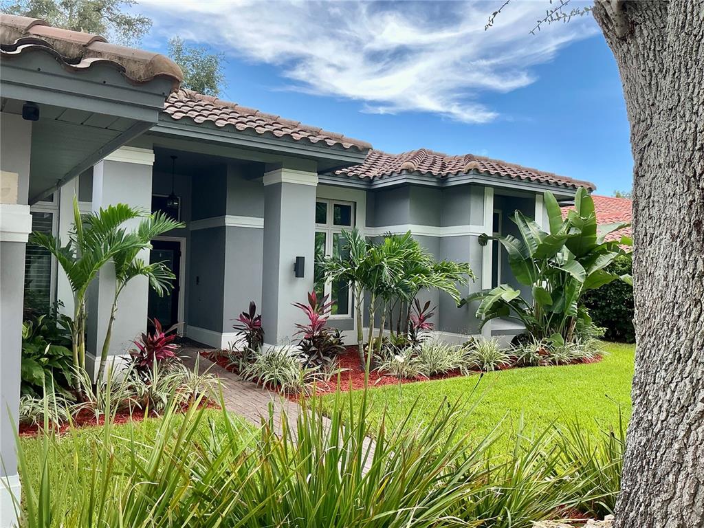 A house exterior features a paved driveway, a three-car garage, and a tiled roof — 126 OLD OAK CIRCLE, PALM HARBOR, FL