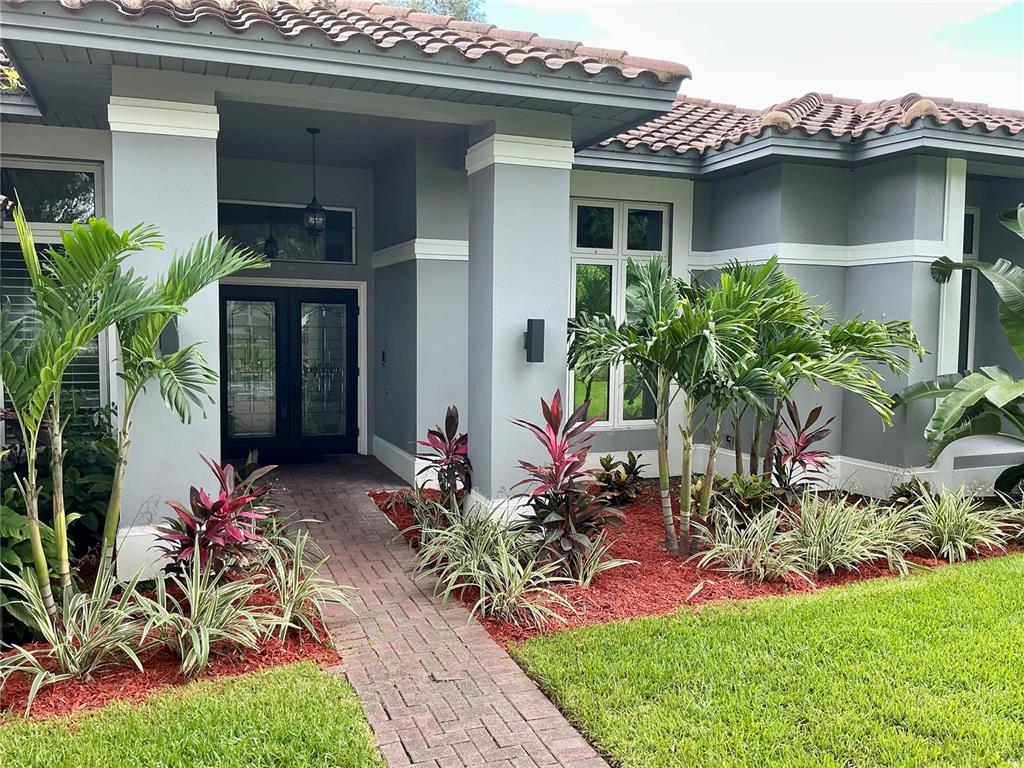 A kitchen with a dark island, white cabinets, marble countertops, and a fireplace — 126 OLD OAK CIRCLE, PALM HARBOR, FL