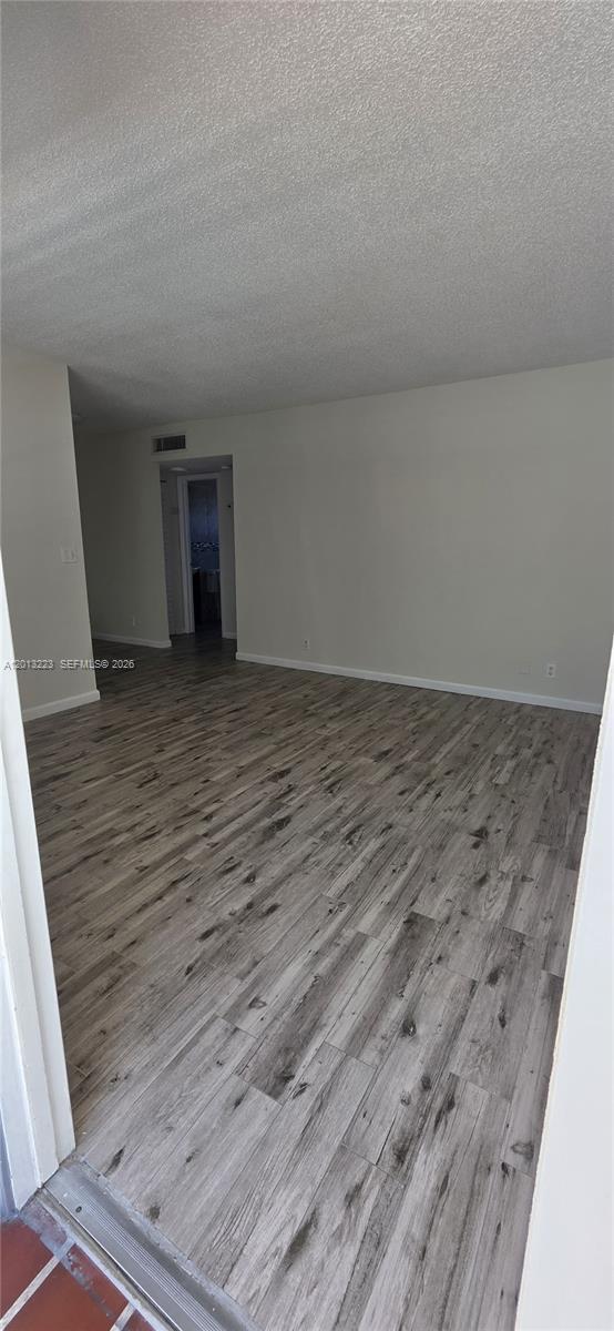An empty room features light gray wood-look flooring and plain off-white walls — 30 SE 4th Ave # 115, Hallandale Beach FL 33009, HALLANDALE BEACH, FL