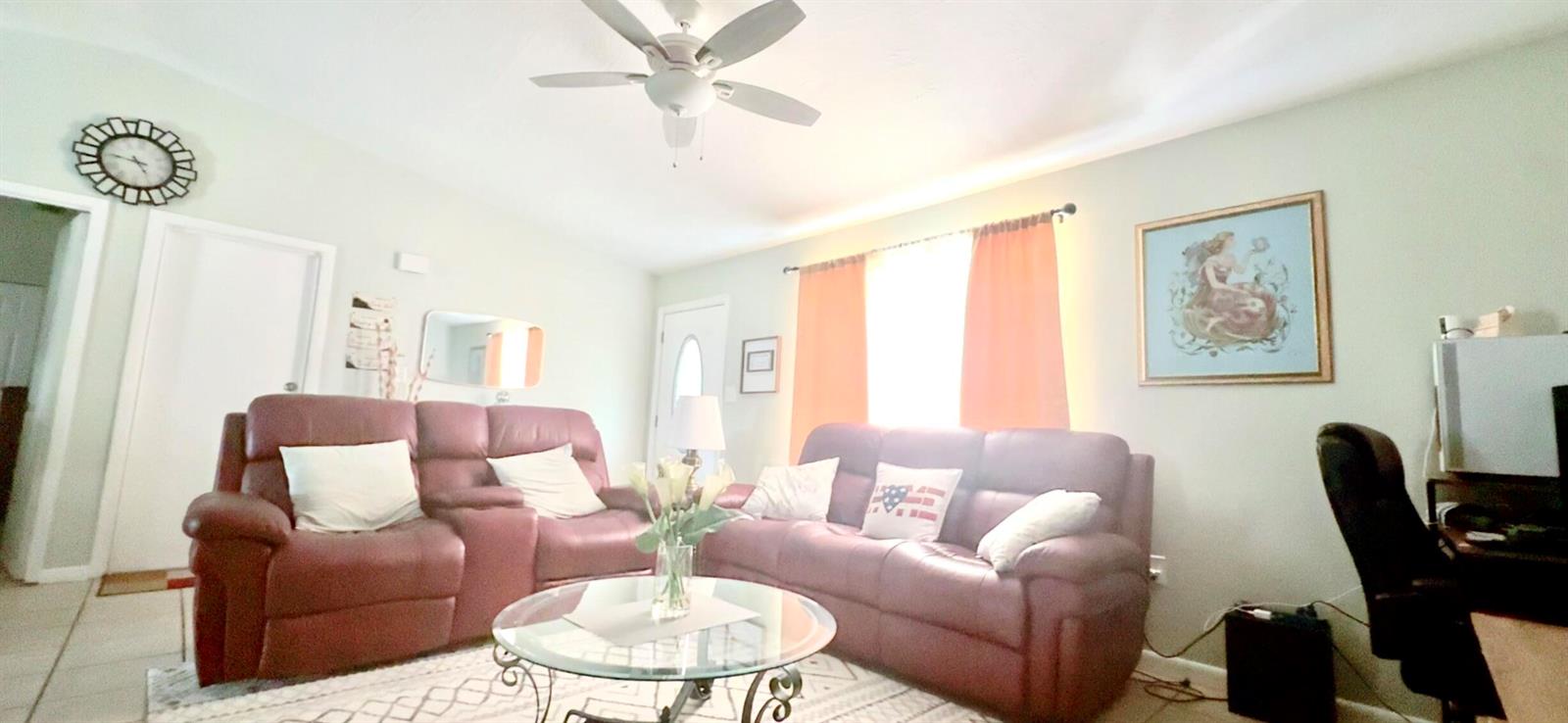 A living room features two maroon leather sofas, a glass coffee table, and a ceiling fan — 617 Thuringer Street NW, Palm Bay FL 32907, PALM BAY, FL
