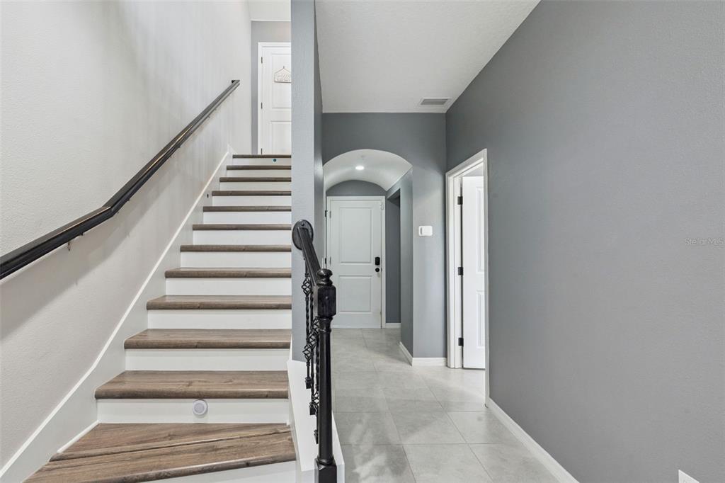 A staircase with wood treads and a black railing leads to a hallway with tile — 476 PORTICO COURT, OVIEDO, FL