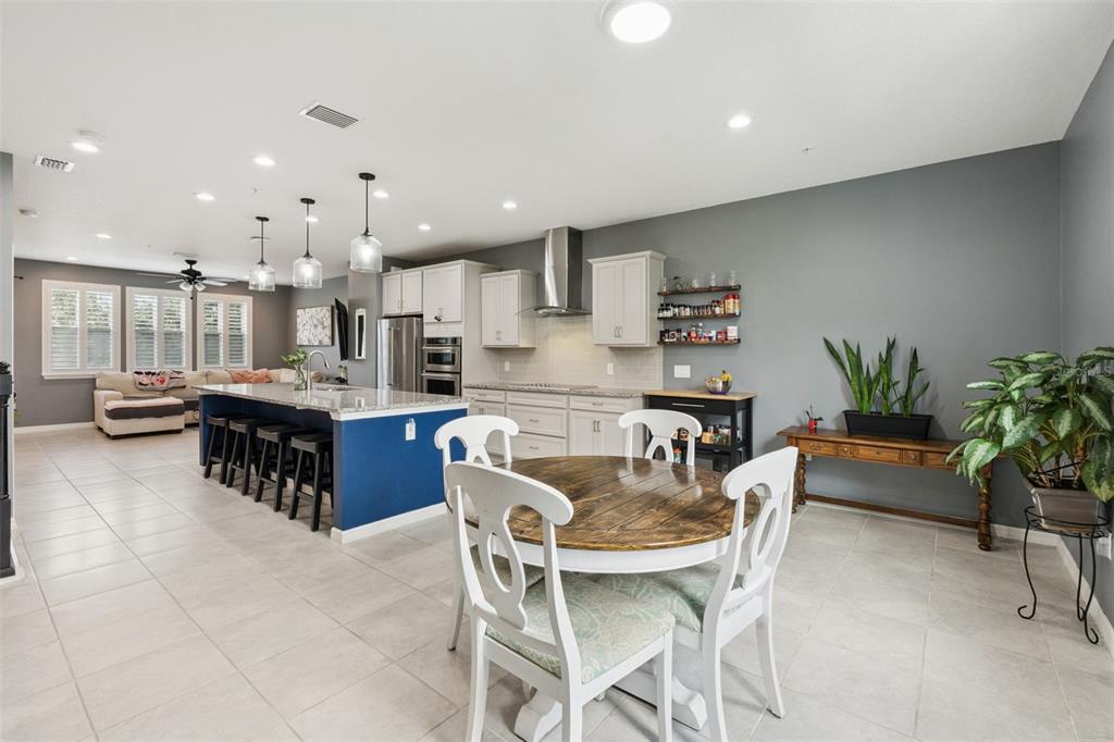 An open-concept kitchen and dining area features a blue island, white cabinets, and tile flooring — 476 PORTICO COURT, OVIEDO, FL