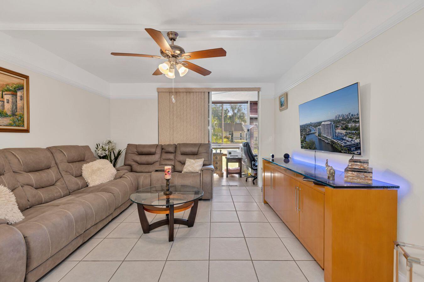A living room features a beige sectional sofa, glass coffee table, and a wall-mounted television — 6850 Royal Palm Boulevard # 106g, Margate FL 33063, MARGATE, FL