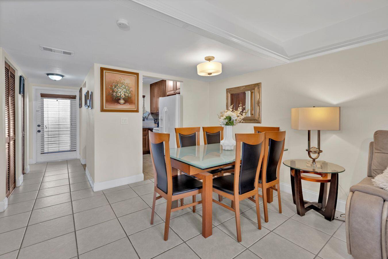 A dining area with a glass-top table, six chairs, and tile flooring near a kitchen — 6850 Royal Palm Boulevard # 106g, Margate FL 33063, MARGATE, FL