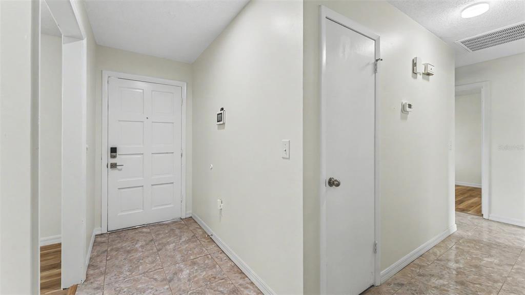 An entryway features a white front door, a closet door, and light-colored tile flooring — 7209 GROVE WAY, LAKELAND, FL
