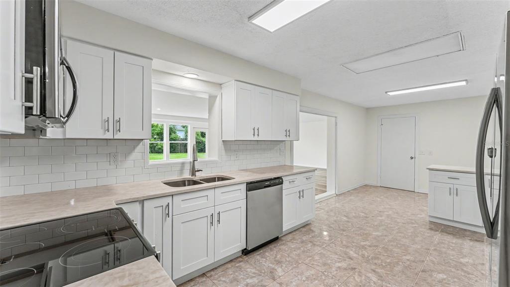 A kitchen features white cabinets, stainless steel appliances, a subway tile backsplash, and tiled floors — 7209 GROVE WAY, LAKELAND, FL
