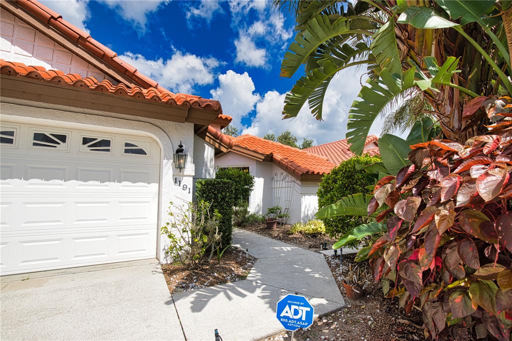 A view of a house exterior with a garage, tiled roof, and a walkway — 1191 HARBOR TOWN WAY, VENICE, FL